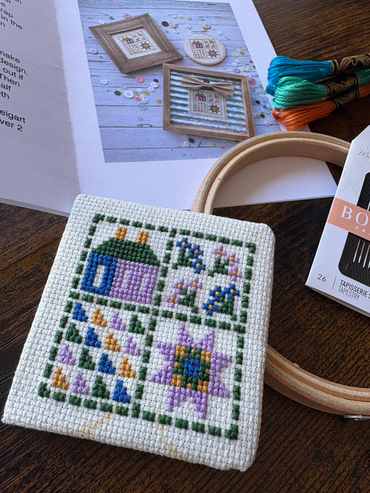 Cross-stitched project with embroidery hoop and thread on a wooden surface